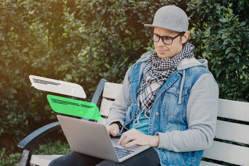 A Caucasian man sits on a bench and communicates on instant messengers and social networks.