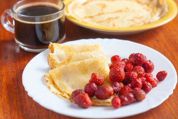 Russian pancakes with berries and coffee on the table