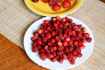 Ripe strawberries on a plate on the table, baked Apple, strawberry and cherry on a yellow plate, top view