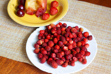 Ripe strawberries on a plate on the table, baked Apple, strawberry and cherry on a yellow plate