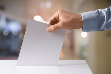 Man putting his vote into ballot box indoors, closeup