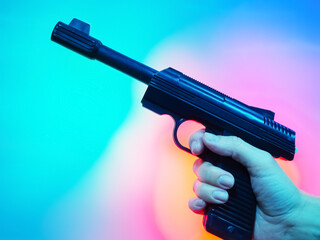 Hand holds black soviet revolver on multicolor background