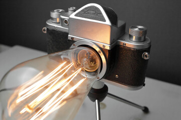 Retro lamp from an old camera with an Edison lamp on a gray background. Concept is a good idea.