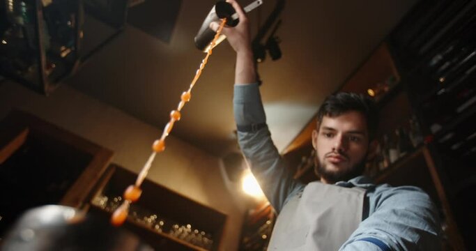 Authentic professional caucasian bartender creating a cocktail drink. Experienced barman pouring alcohol beverage in shaker - food and drink concept close up 4k footage