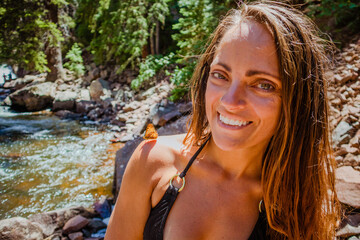 Obraz premium Young woman in a bikini with an orange butterfly on her shoulder