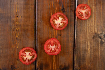 tomato slices on a brown wooden background, top view, text space, fresh vegetables