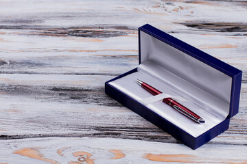 Luxury pen in a blue gift box. White wooden background.