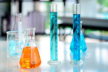Orange solution Chemicals in flask and blue chemicals in cylider tubes placed on the table were prepared for chemical experiments in chemical laboratories.