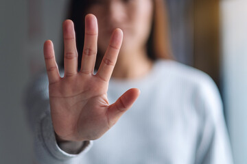 Closeup image of a woman outstretched hand and showing stop hand sign - obrazy, fototapety, plakaty