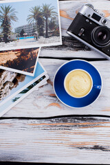 Topview cup of cappuccino with vintage photo camera. Summer vacation photos. White wooden background.