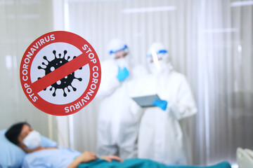 Closed up Stop Coronavirus sign stuck in front of the emergency room of a patient infected with Covid 19 virus and Medical team in Personal Protective Equipment or PPE clothes and healing inside room.