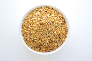 Dry oatmeal in a white bowl on a white background. Healthy food. Top view.