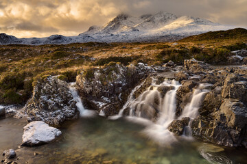 Dramatic clouds on the Isle of Skye with the Cuillin mountain range covered in snow taken from a waterfall near Sligachan bridge.