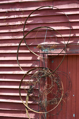 Rusty Metal Hoops and wire hanging over the door of a red shingled shed in Maine