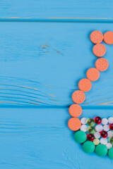 Jug shape made of medicine pills. Blue wooden background.