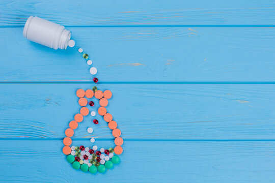 Pouring Pills From Medicine Bottle To A Jug. Blue Wooden Background. Topview Flay Lay Copy Space.