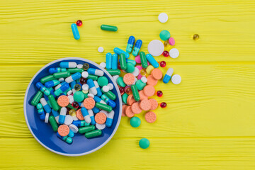Pile of multicolored tablets on a yellow background. Topview flay lay.