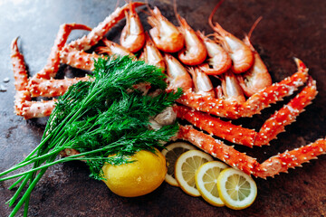 Fototapeta na wymiar On the table are shrimp, crab, lemon and herbs. Table of reddish color.