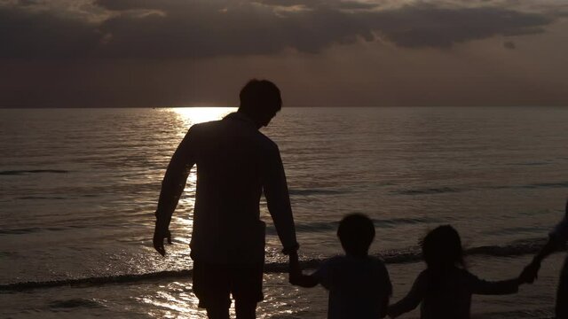 Silhouette of happy asian family running for relax on vacation together in the beach in evening with sunset, parents and kid happiness leisure and fun tropical with sunrise in summer, travel concept.