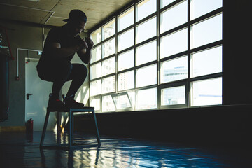 Fototapeta na wymiar sports man jumps on a special platform in the gym opposite the window. Crossfit silhouette shot