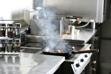 Cooking meat on frying pan in restaurant kitchen