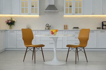 Table with orange chairs in modern kitchen interior