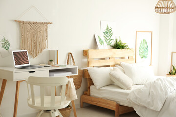 Stylish room interior with workplace and bed