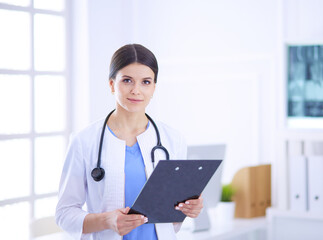 Young smiling female doctor with stethoscope holding a folder at doctor's office