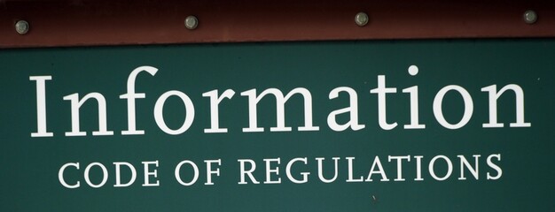 Closeup shot of a dark green sign with text [Information, CODE OF REGULATIONS]
