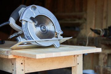 a worker using a circular saw works with wood in a carpenter's workshop