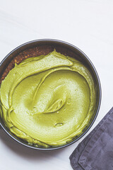 Cooking raw vegan matcha cheesecake on white background.