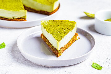 Piece of raw vegan matcha cheesecake on a gray plate.