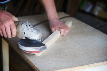 a worker using a sanding machine works with wood in a carpenter's workshop