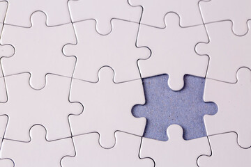 Obraz premium Missing jigsaw puzzle pieces. Business concept. Fragment of a folded white jigsaw puzzle and a pile of uncombed puzzle elements against