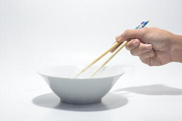 Hand using chop stick against white bowl on isolated white background