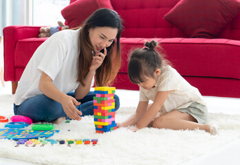 asian mother teaching her young daughter to play puzzles at home. homeschooling and family together concept