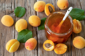 Homemade organic jam in glass jar and ripe apricots on wooden rustic table