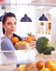 Smiling woman taking a fresh fruit out of the fridge, healthy food concept