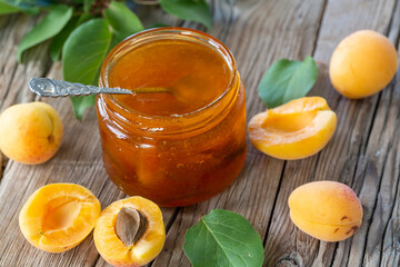 Homemade organic jam in glass jar and ripe apricots on wooden rustic table