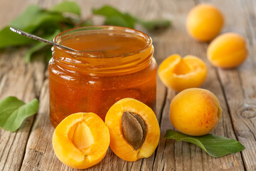 Homemade organic jam in glass jar and ripe apricots on wooden rustic table