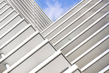 The striped elements of the modern building create a geometric pattern.Urban abstract architecture in the minimalism style.A fragment of the hotel exterior facade is white against the blue sky.
