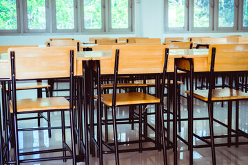Situation of Covid-19 disease outbreak resulted in inability organize teaching learning in college. Lecture school empty classroom with desks chair iron wood when student close stay at home