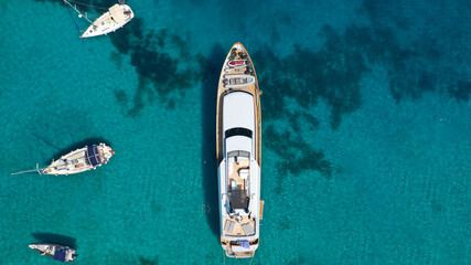 Aerial drone photo of yacht anchored in popular bay and beach of Super Paradise, Mykonos island,...