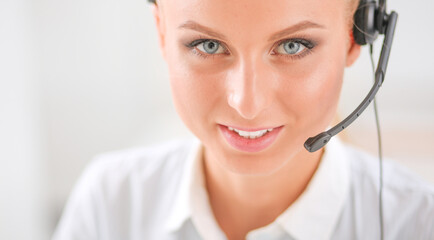 Portrait of pretty young female operator sitting at office desk with headset