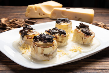Homemade rondelli with four cheese and mushuroom sauce in white plate on rustic white wooden table background, soft light