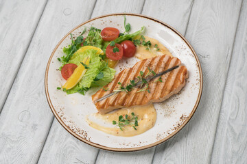 One piece of baked salmon grilled pepper lemon and salt on a white plate
