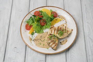 One piece of baked salmon grilled pepper lemon and salt on a white plate