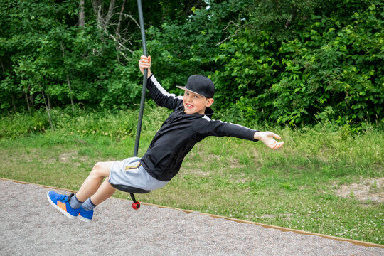 Sporty child smiling riding a zip-line at an playground in a public park.