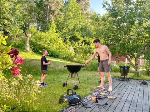 Teenager and children relaxing.  Hot summer garden marshmallows  barbecue grill in meadow backyard.