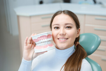 Beautiful young woman in dental chair. Smiling and satisfied patient at dentist's office after treatment. Healthy teeth, dental care concept.